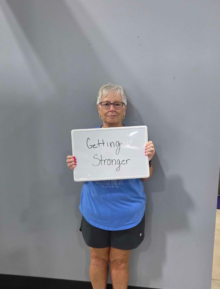 Ageless Fitness member holding a whiteboard sharing what they’re getting stronger for